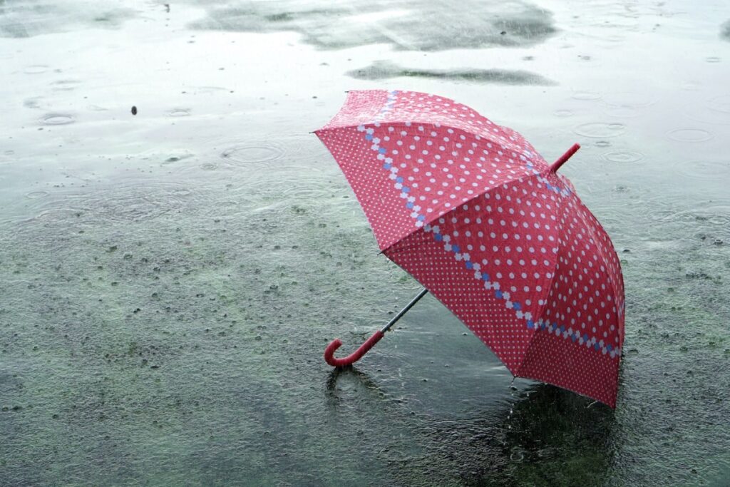 Umbrella on rainy day - The raindrops falling on an umbrella which put on the ground and copy space, feeling lonely and sad concept. (Umbrella on rainy day - The raindrops falling on an umbrella which put on the ground and copy space, feeling lonely